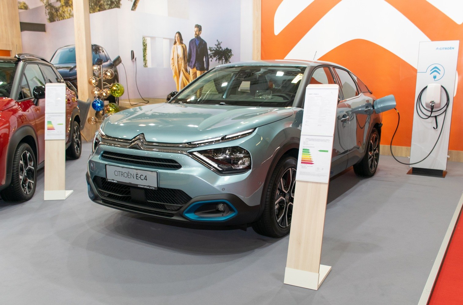 Electric crossover front view with LED headlights and charging station connection.
