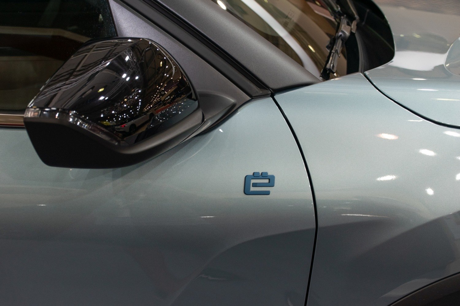 Close-up on side mirror and ë electric badge on car body.