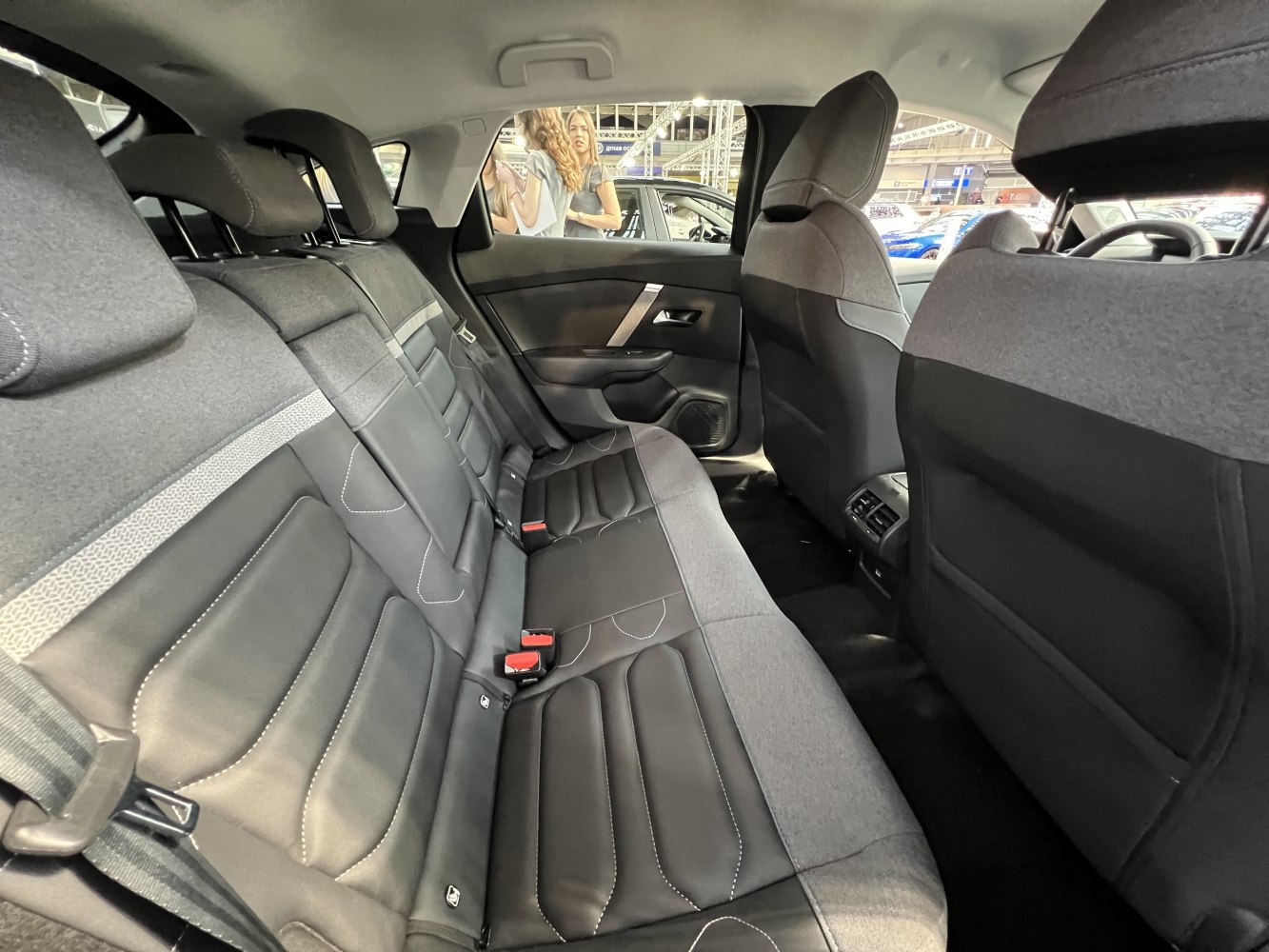 Rear passenger seat interior with leather and fabric upholstery, headrests, and ventilation controls.