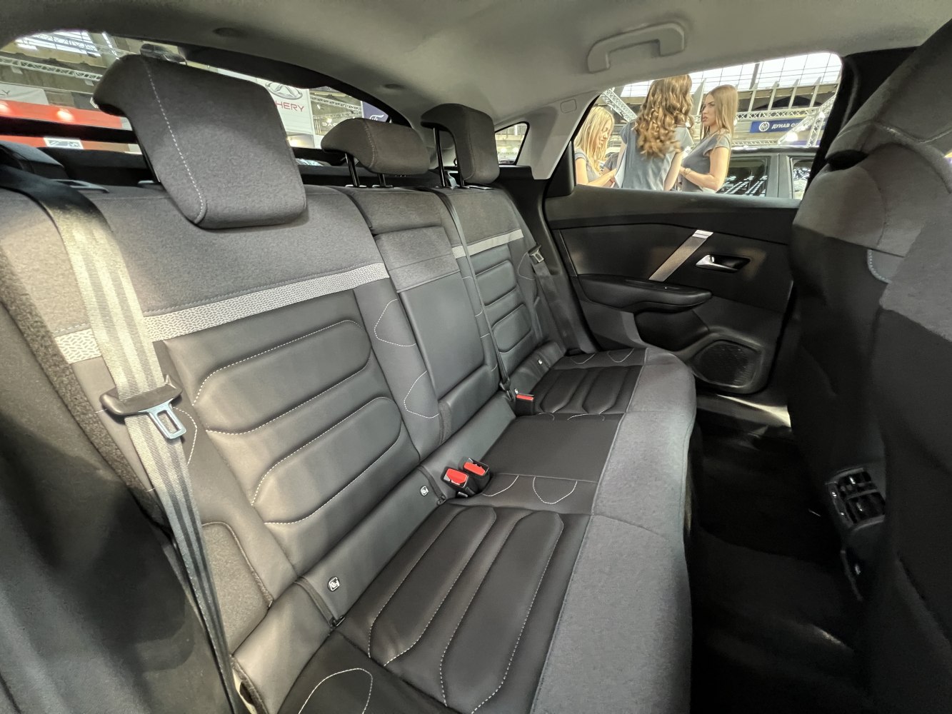 Rear seating area with black fabric and leather upholstery, headrests, seatbelts, and door panel.