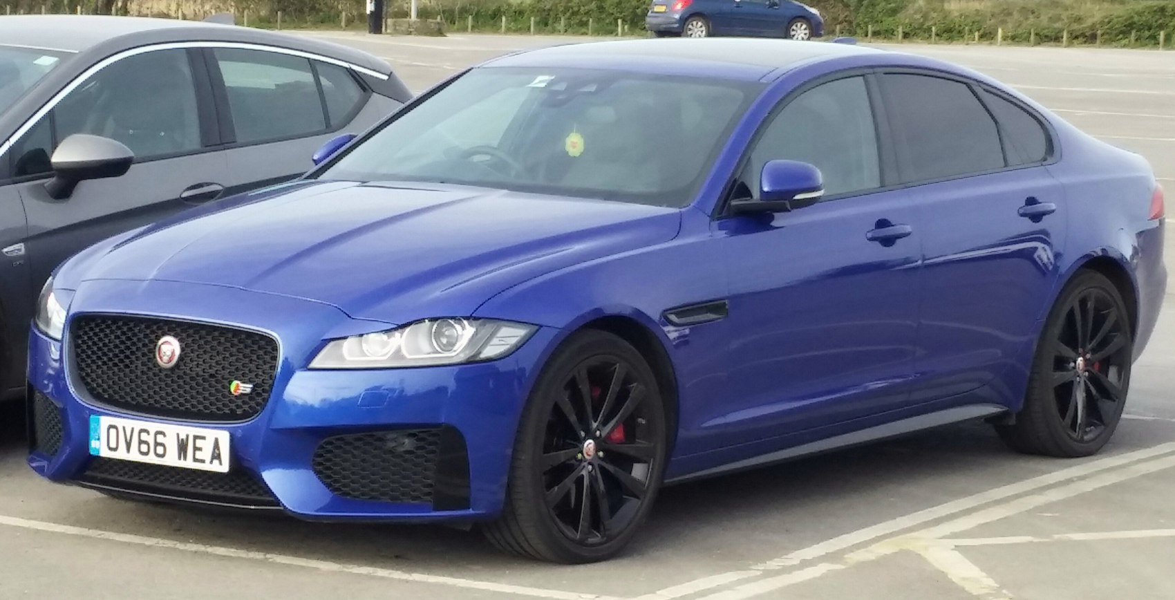 Blue luxury sedan with black alloy wheels and sporty front grille.