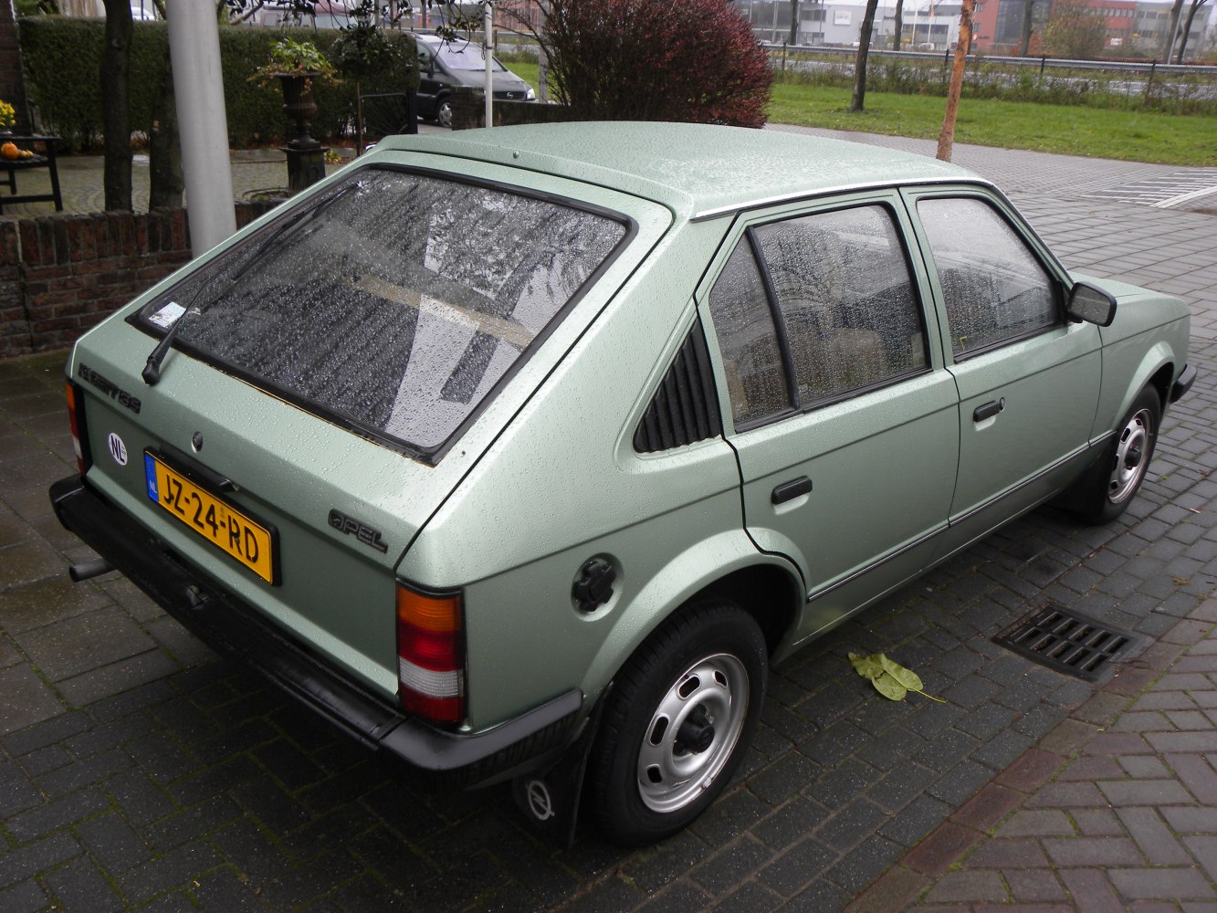 Rear-side hatchback with window louvers and steel wheels in rain