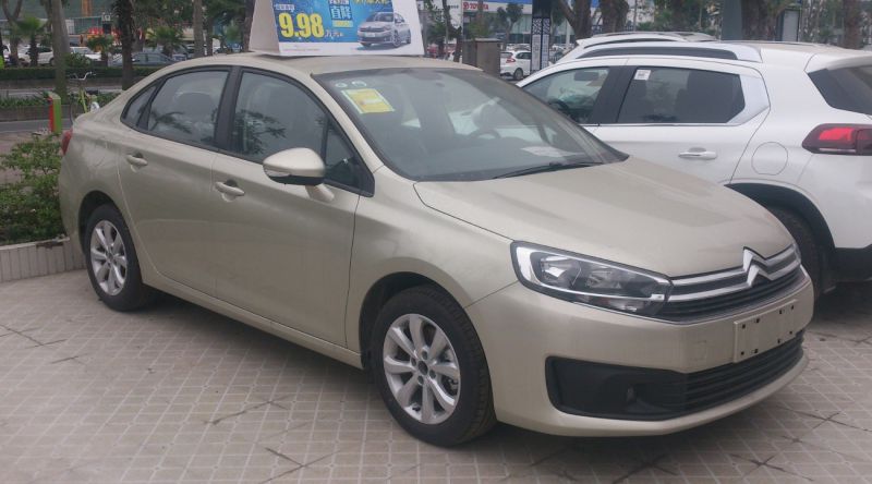 Front side view of metallic beige sedan with distinctive headlights and grille