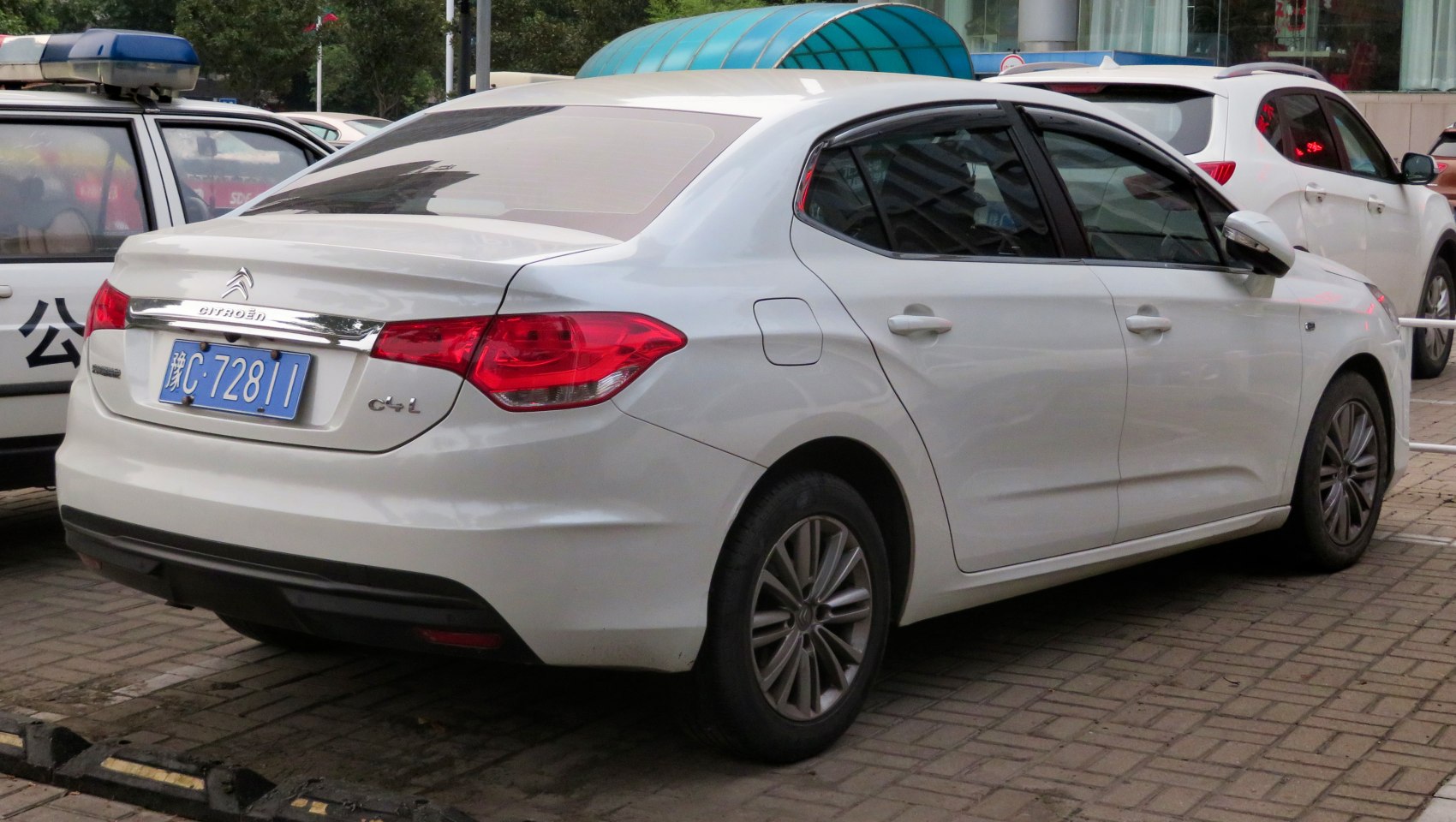 Rear and side view of white sedan with alloy wheels.