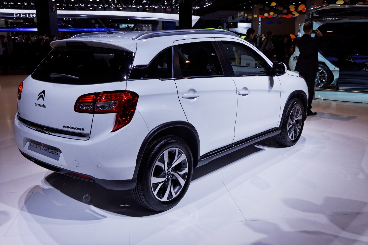 Rear side view of white SUV with alloy wheels and roof rails.