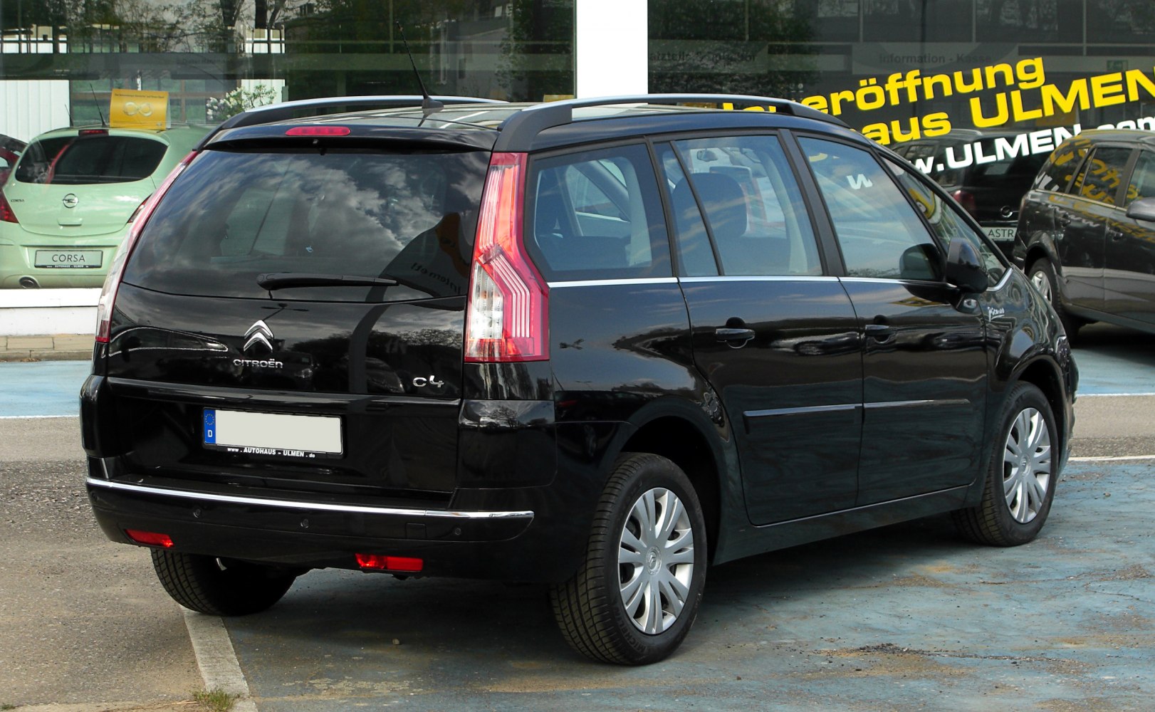 Rear view of black multi-passenger vehicle with vertical tail lights and roof rails