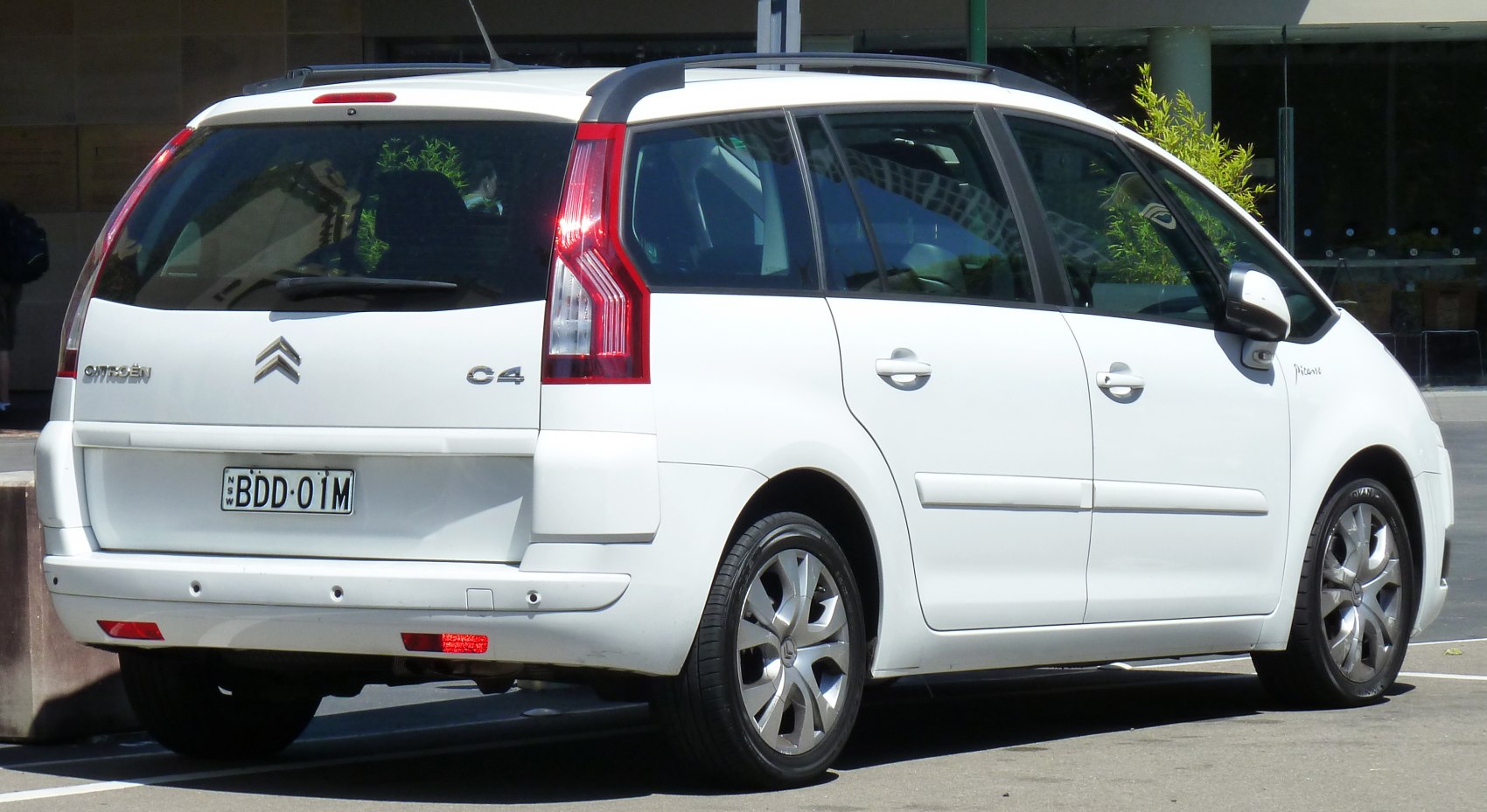 Rear view of white MPV featuring vertical taillights and roof rails