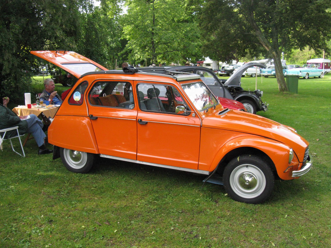 Orange vintage four-door car with open rear hatch and fabric sunroof