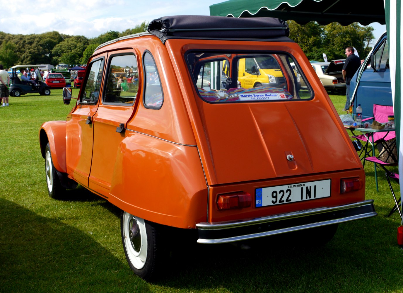 Retro bright orange vintage hatchback with folded canvas roof and whitewall tires