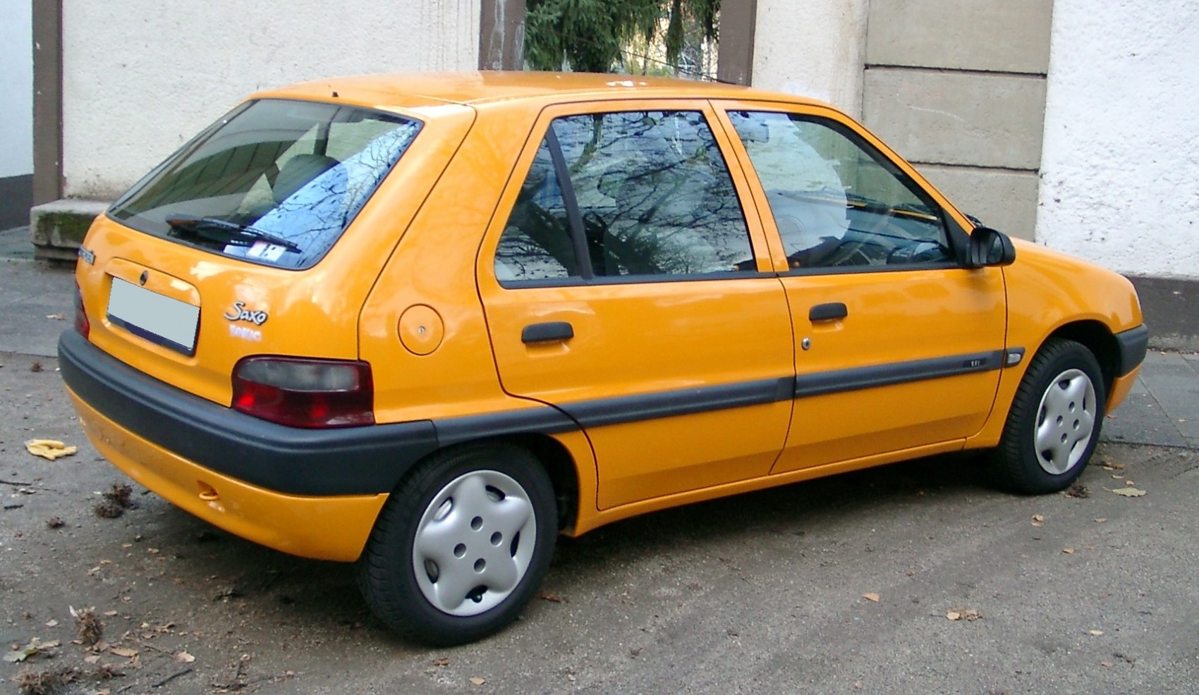 Rear and side view of a yellow 5-door hatchback with black trims and silver wheel covers