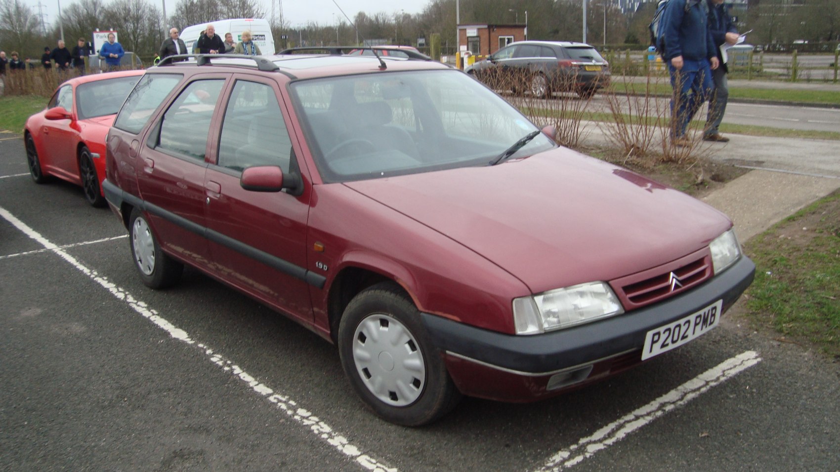 Red station wagon, 1995 model, features roof rails and hubcaps