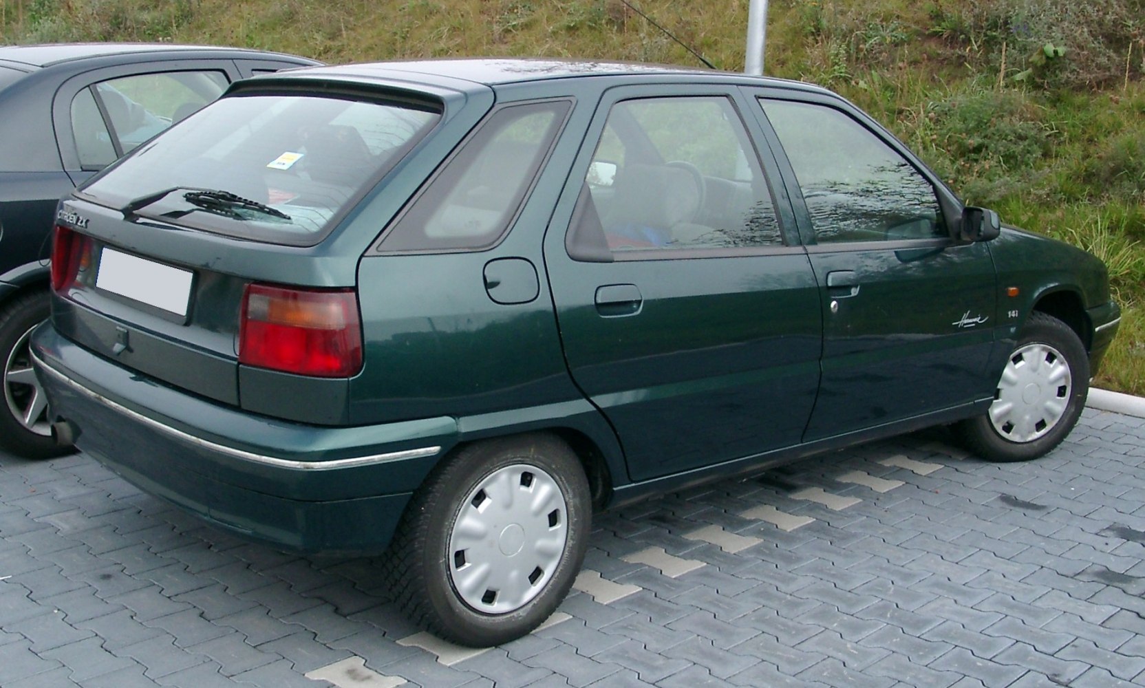Rear-side view of a 1990s 5-door compact hatchback with distinct tail lights and wheel covers