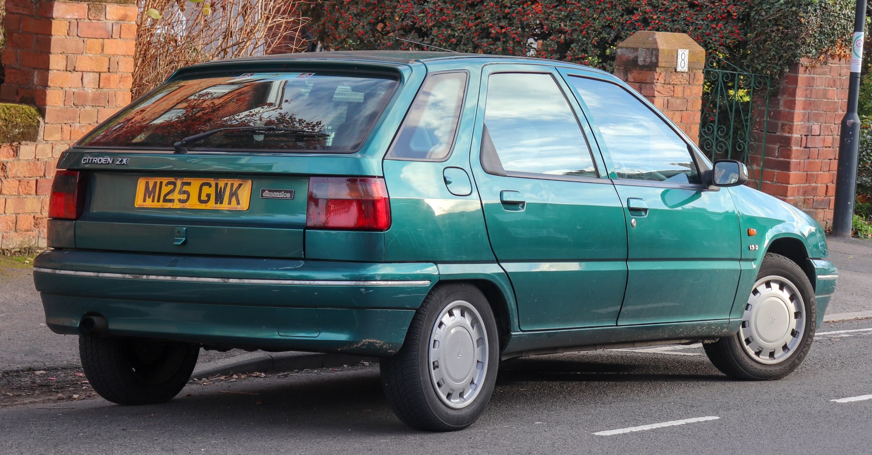Rear right side view of a green 5-door hatchback with distinct rear lights and windshield wiper.