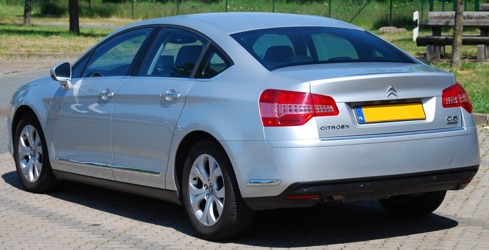 Silver sedan rear side view with distinctive tail lights and chrome accents
