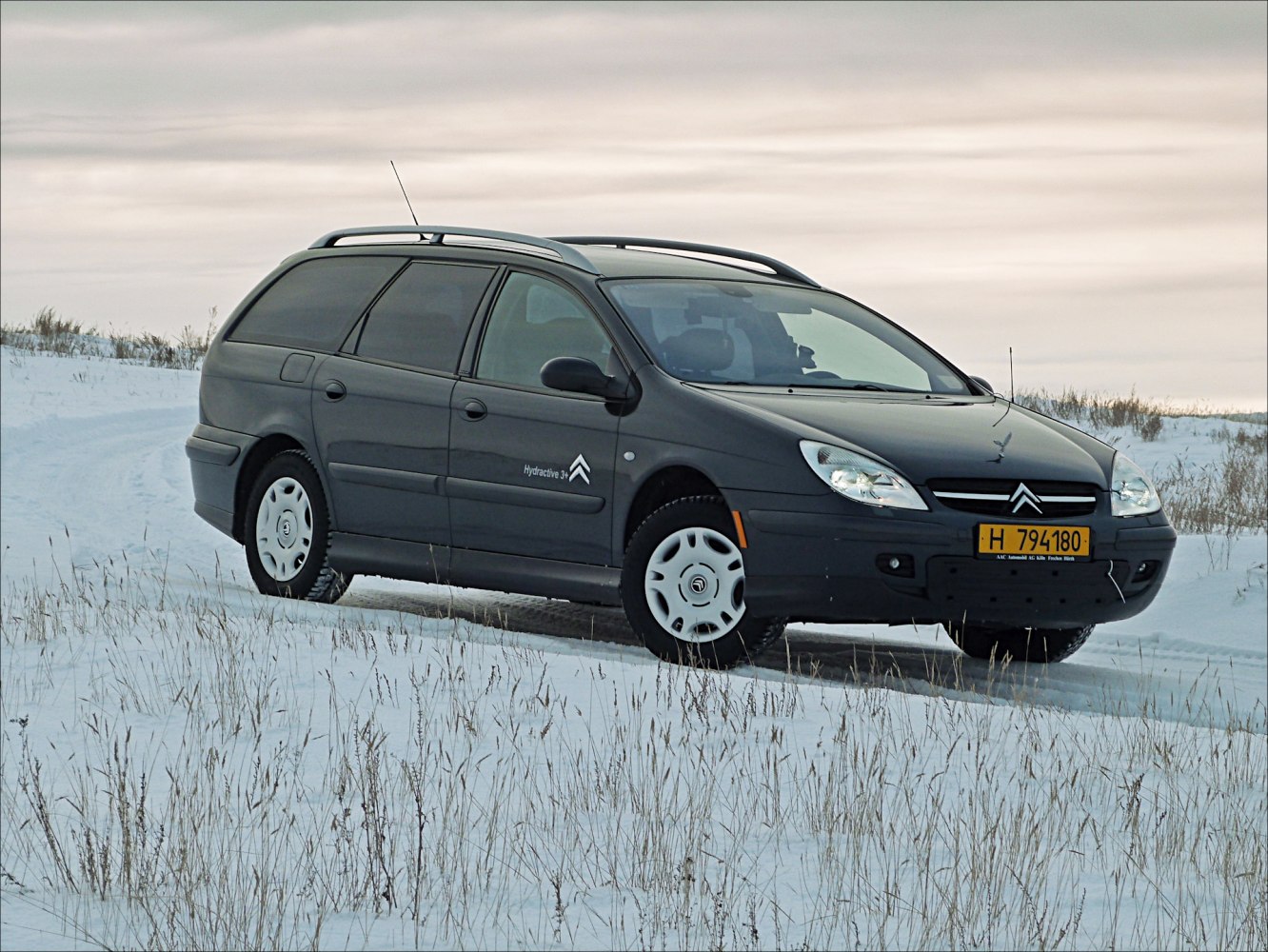 Black station wagon with roof rails and winter tires on snowy terrain