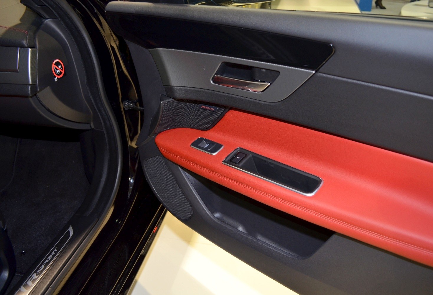 Interior door panel with red leather trim and Meridian speaker