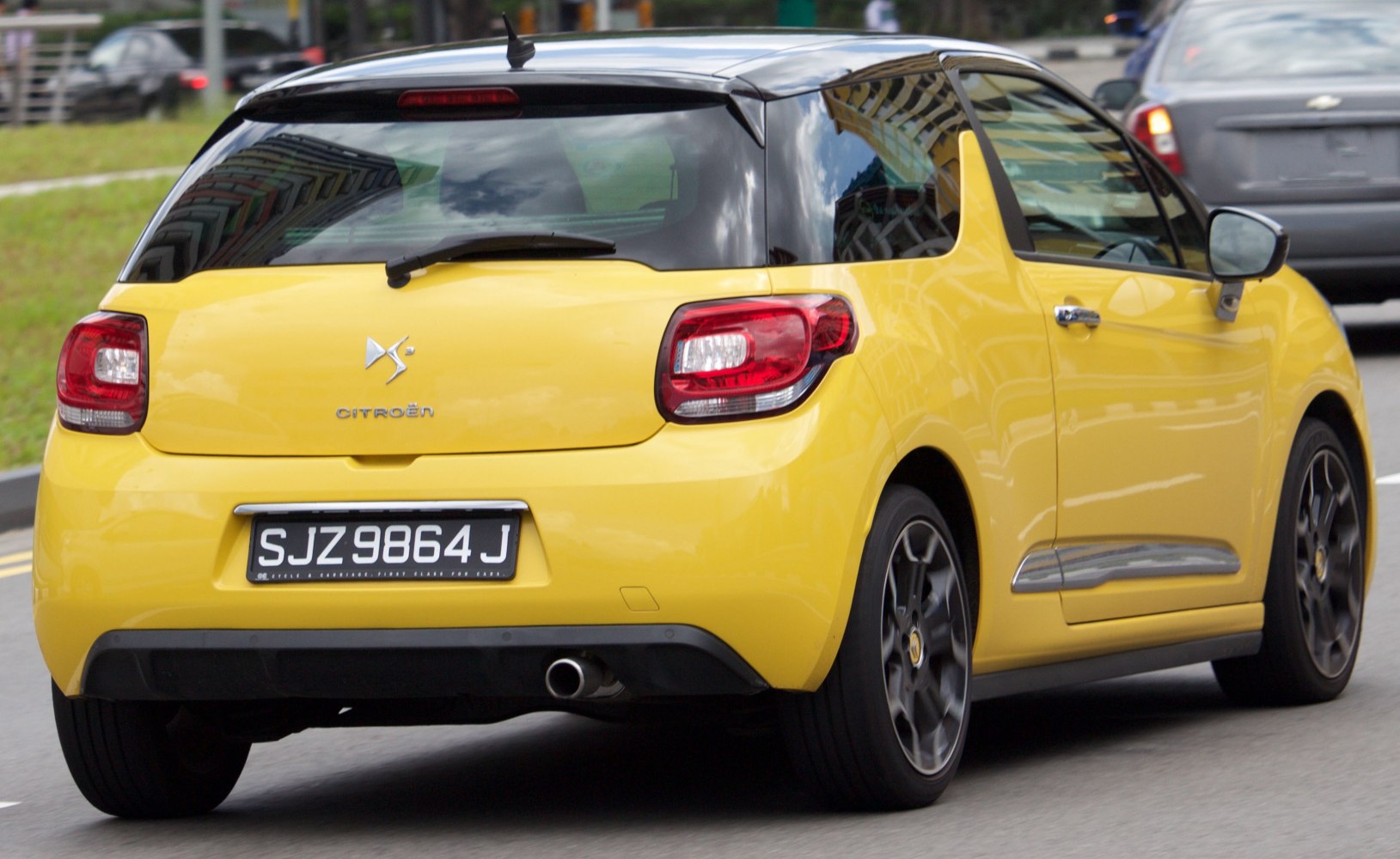 Rear view of a yellow hatchback with black roof and sporty alloy wheels