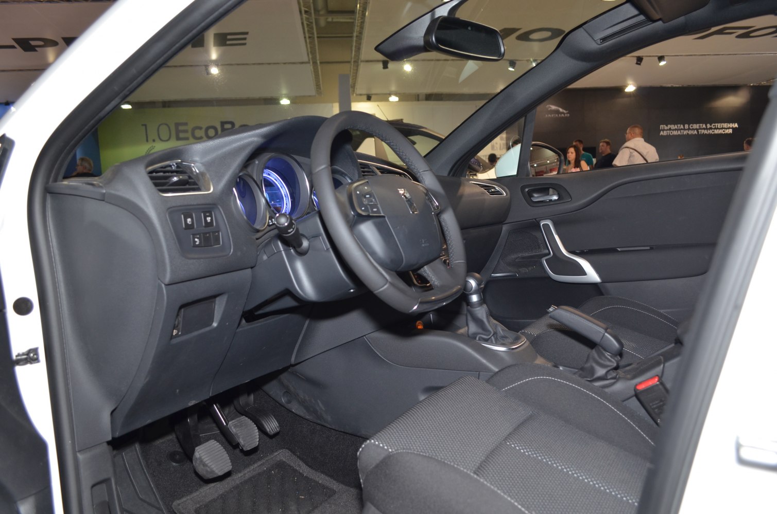 Interior cockpit showing steering wheel, dashboard, pedals, and front seats.