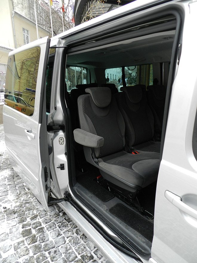 Sliding door open showing multi-row passenger seats inside a van.