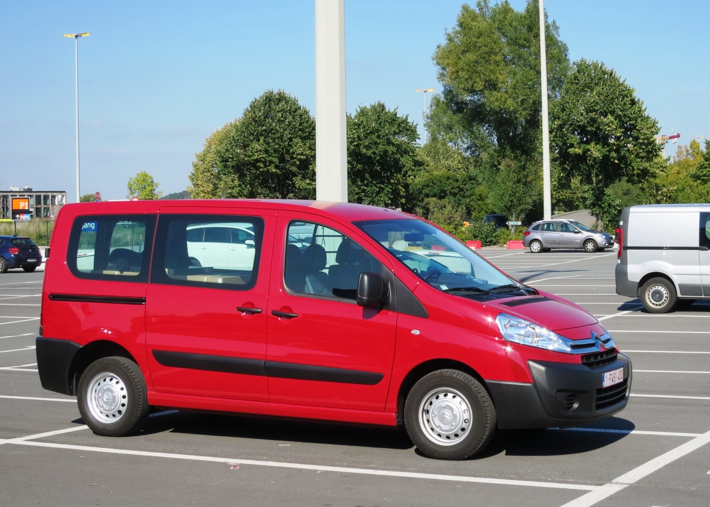 Side profile of red van with sliding door and black bumper trim