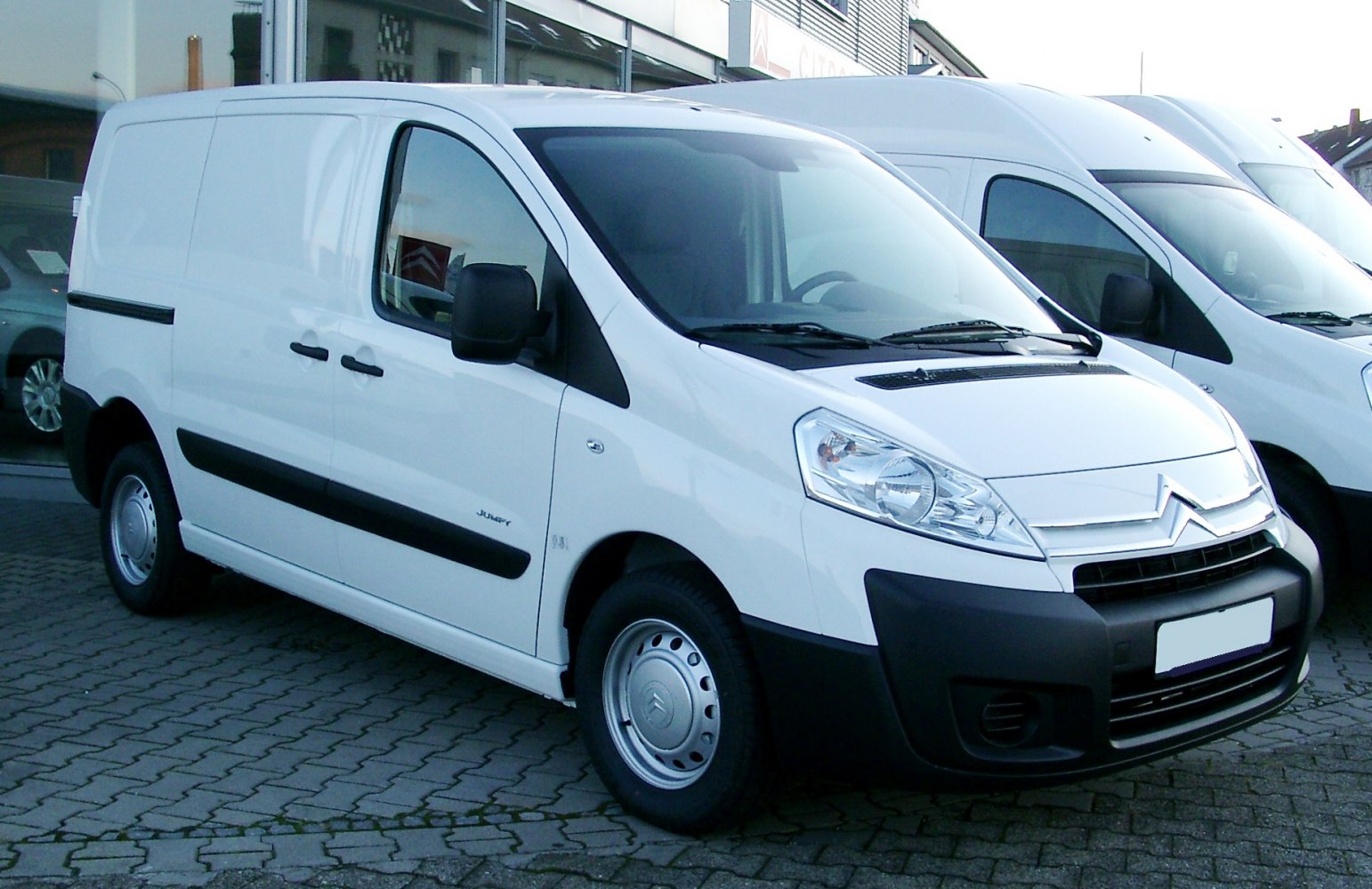 Front and side view of a white cargo van with smooth body panels and prominent headlights