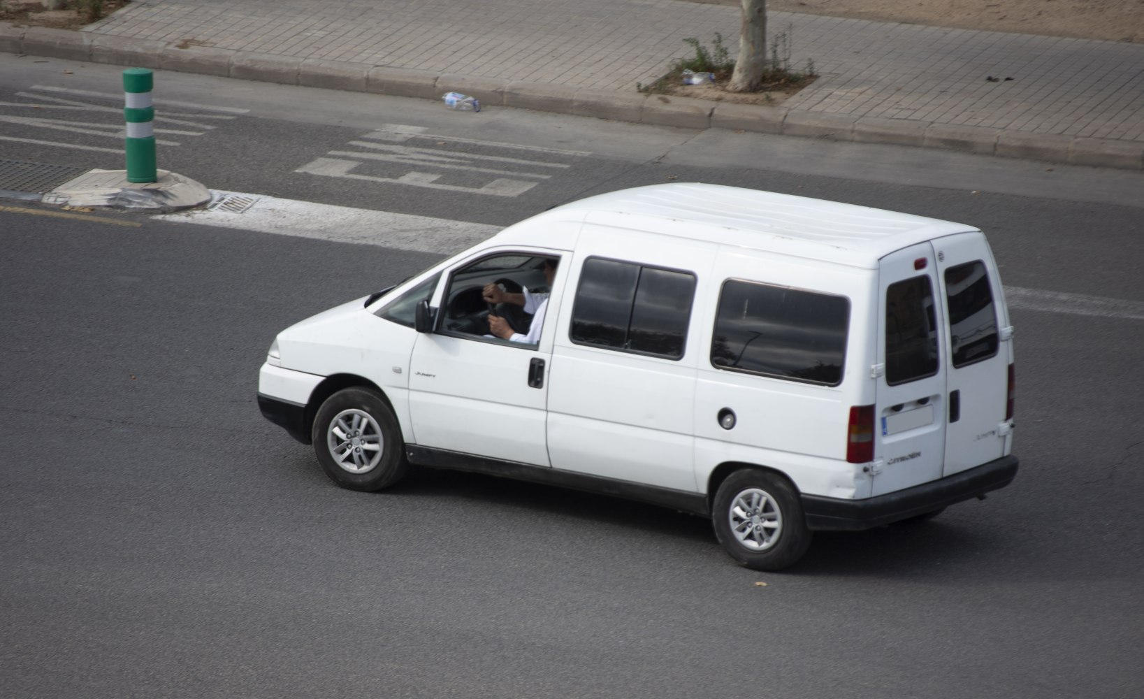 White passenger van with side windows and alloy wheels.