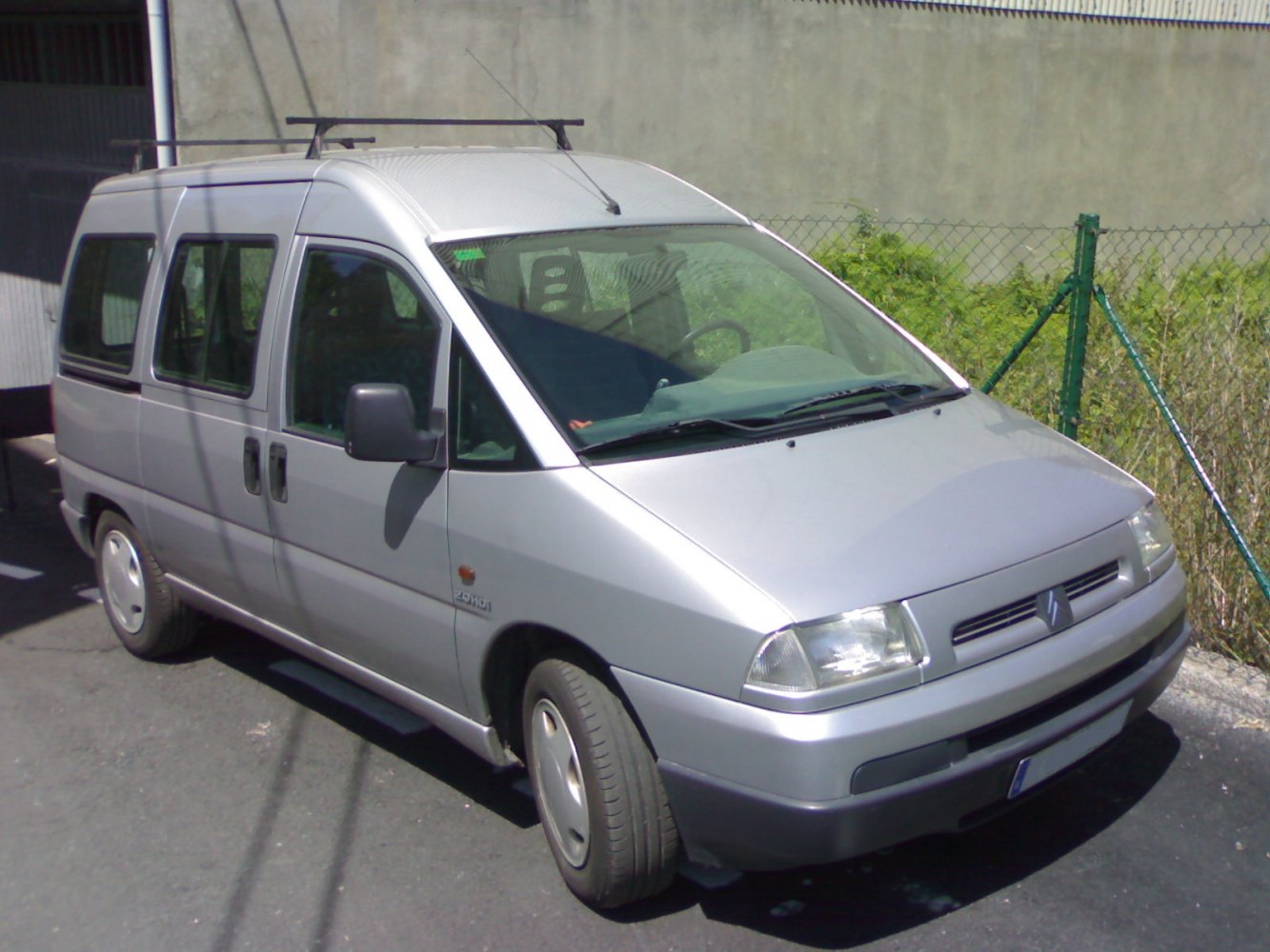Older model silver van with sliding doors and roof rack