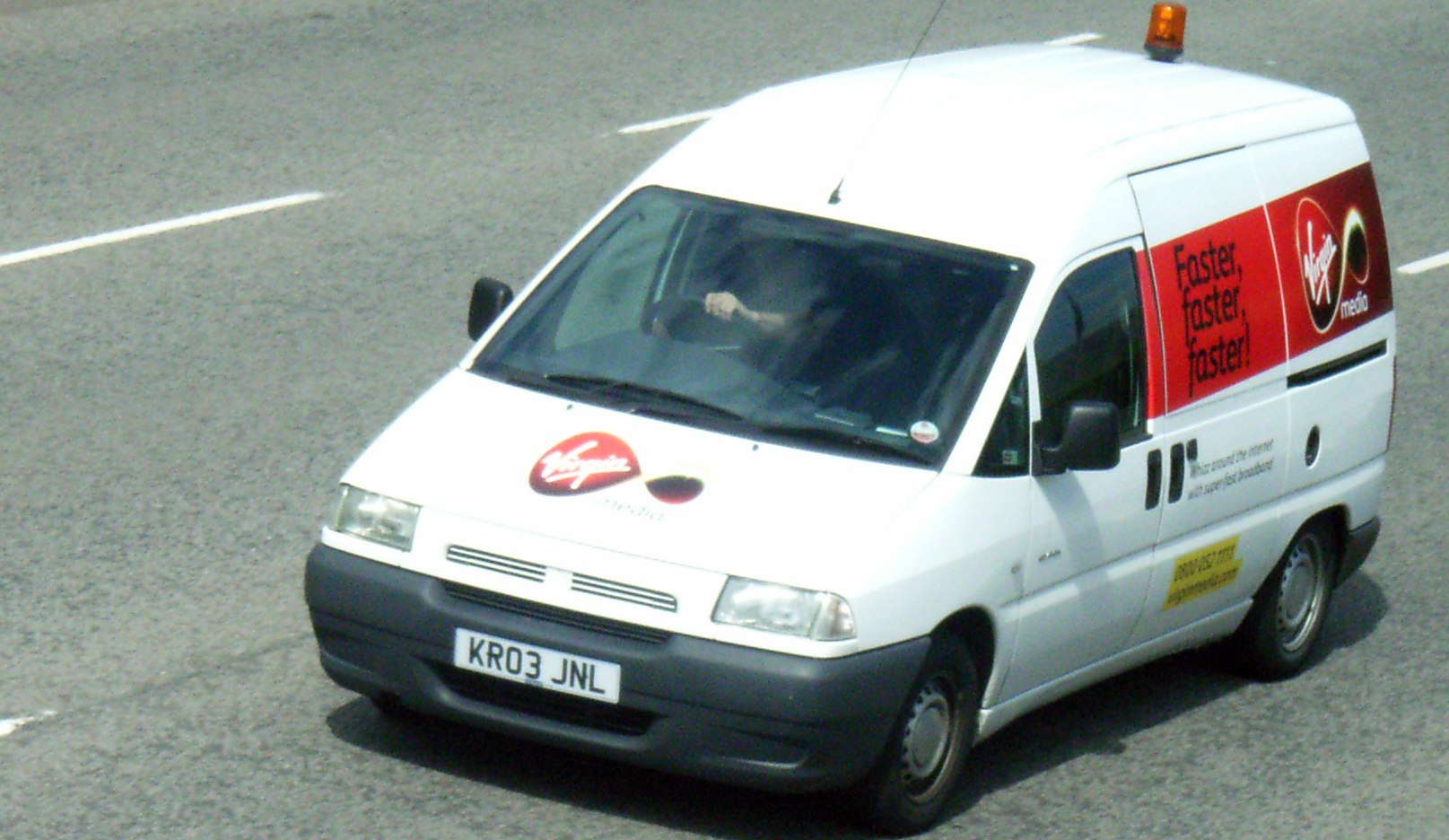 White delivery van with advertising decals and roof beacon