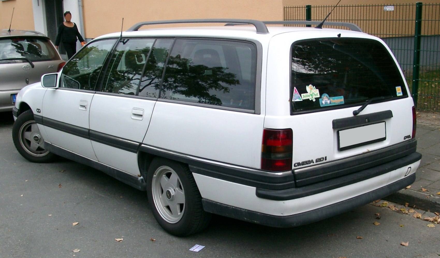 Rear-side view of white station wagon with roof rails and dark taillights
