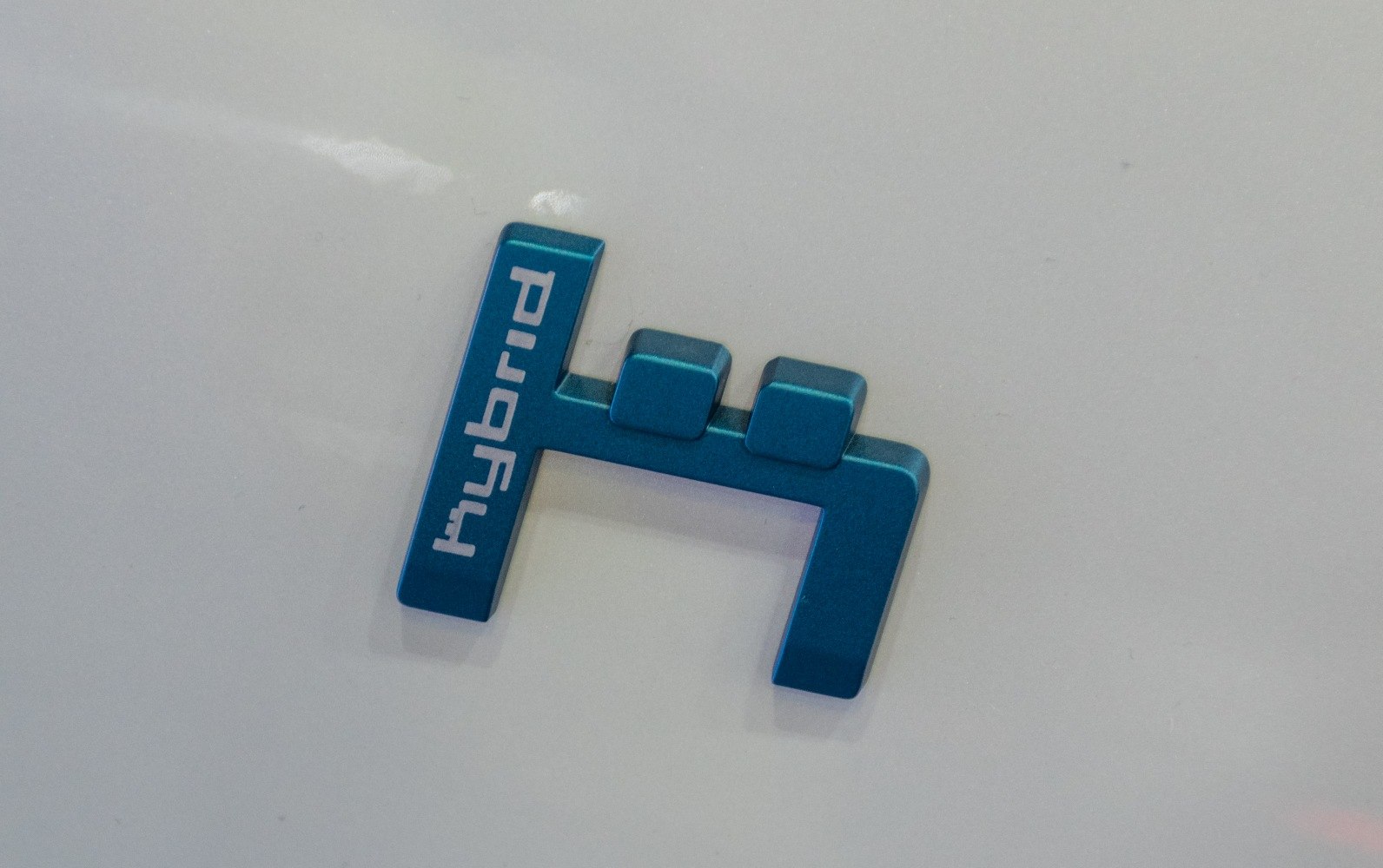 Blue hybrid emblem badge on white vehicle surface