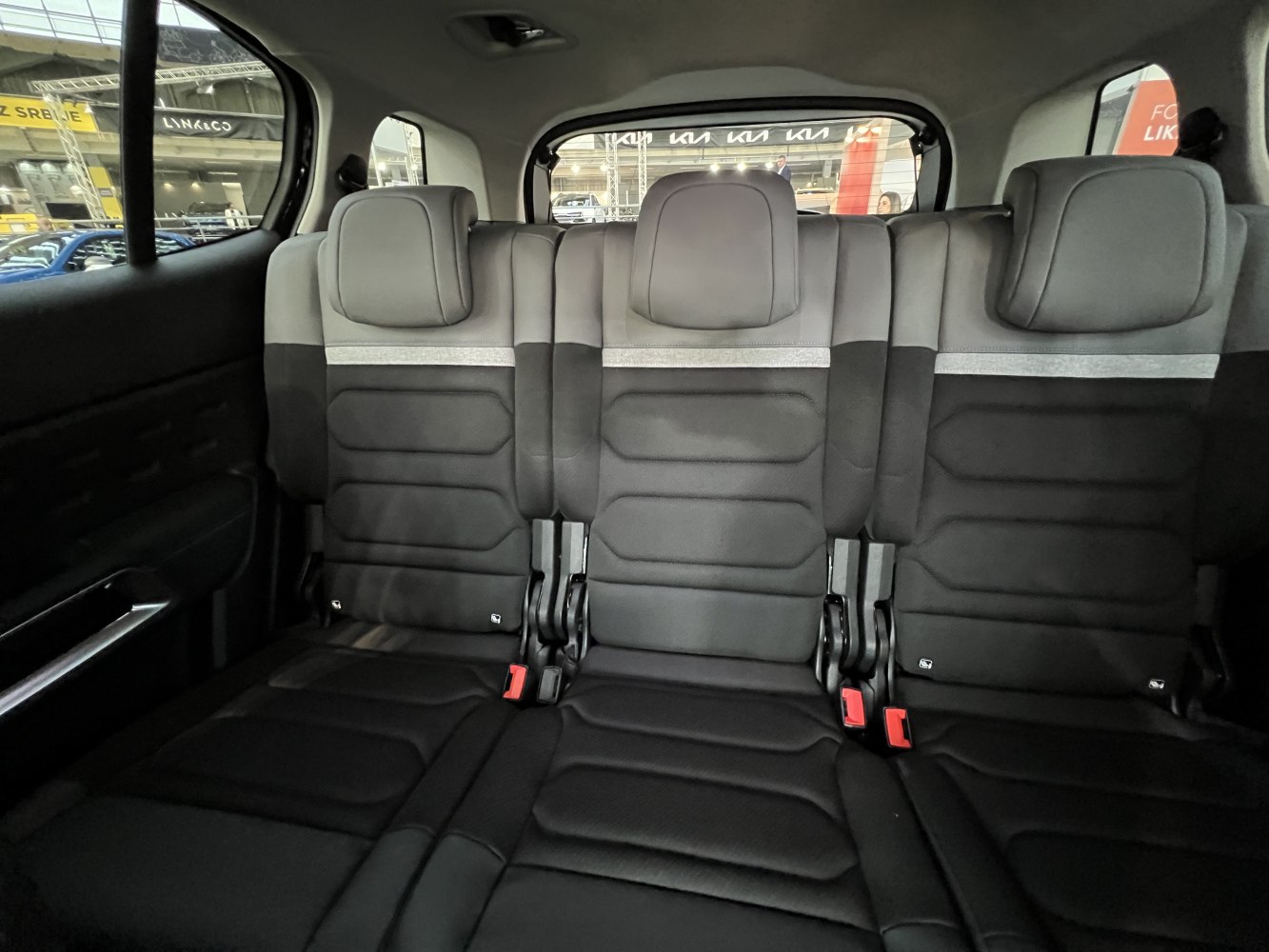 Rear interior showing three upholstered seats with headrests and seat belts