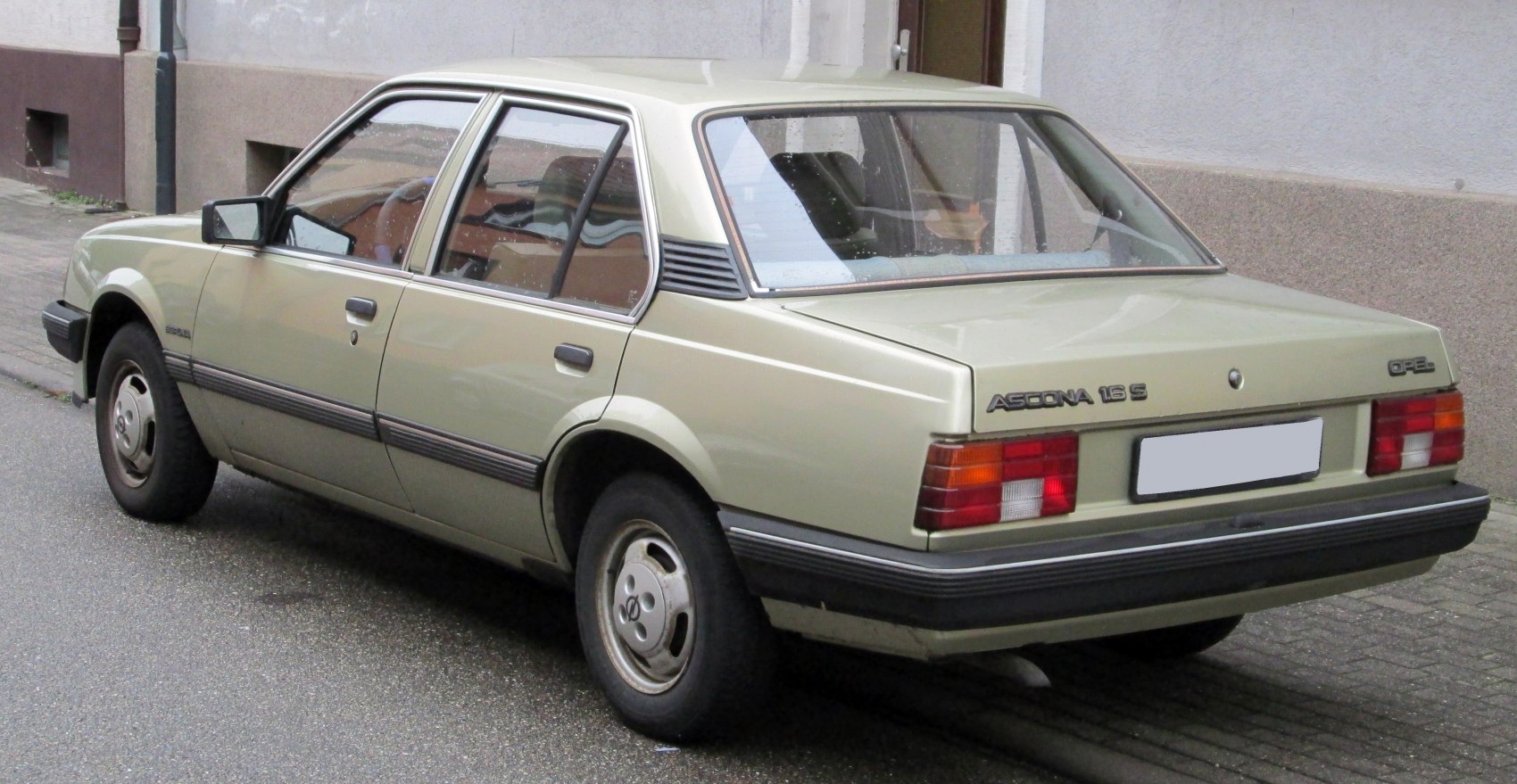 Rear and side view of a 1980s beige sedan with classic taillights and hubcaps