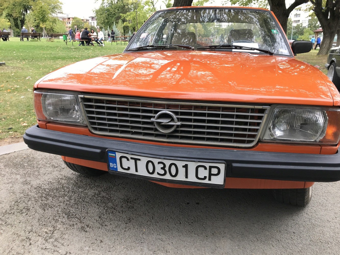 Front grille and rectangular headlights of a vintage orange car.