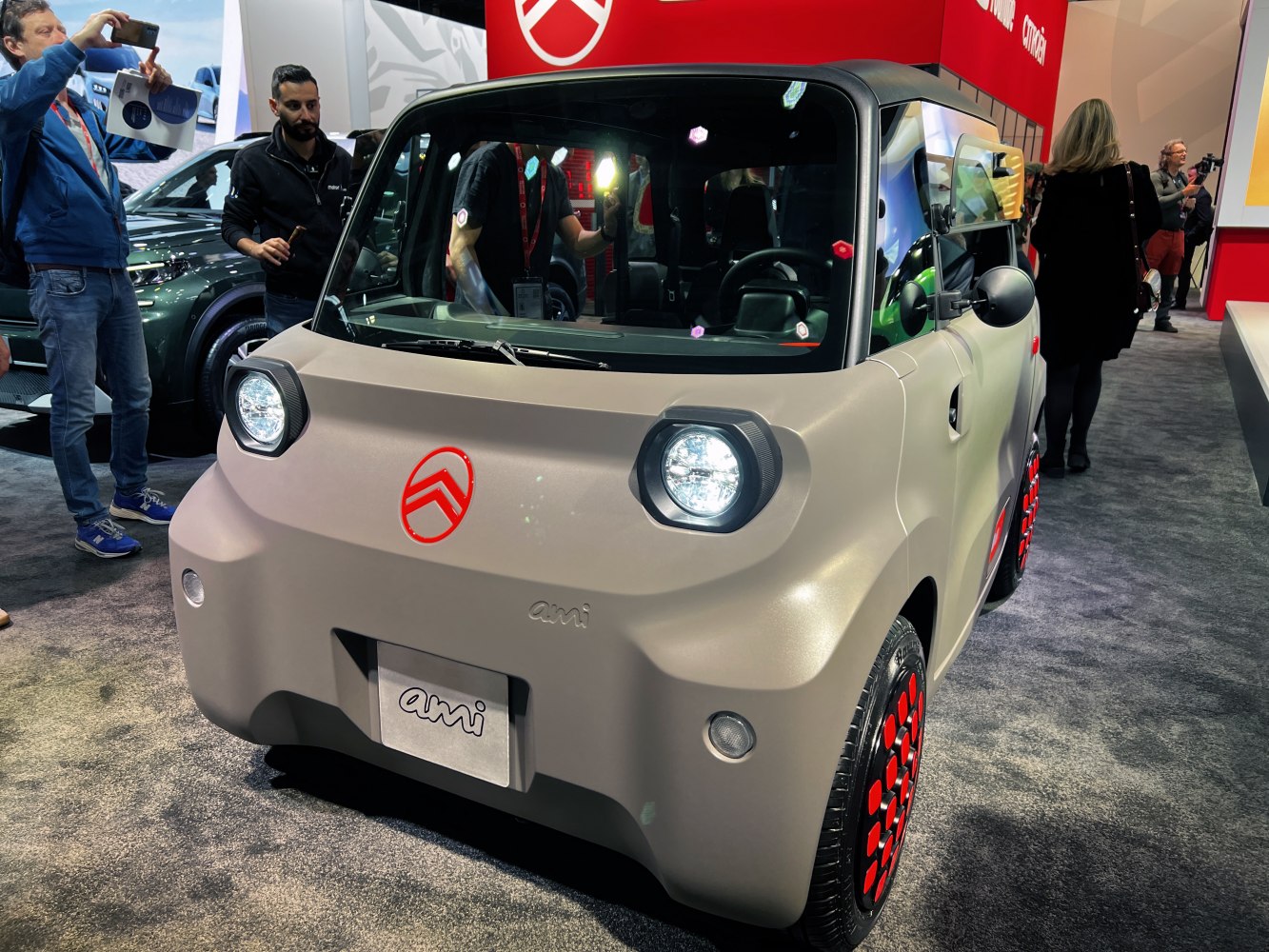 Compact electric vehicle with cubic headlights and red-accented wheels.