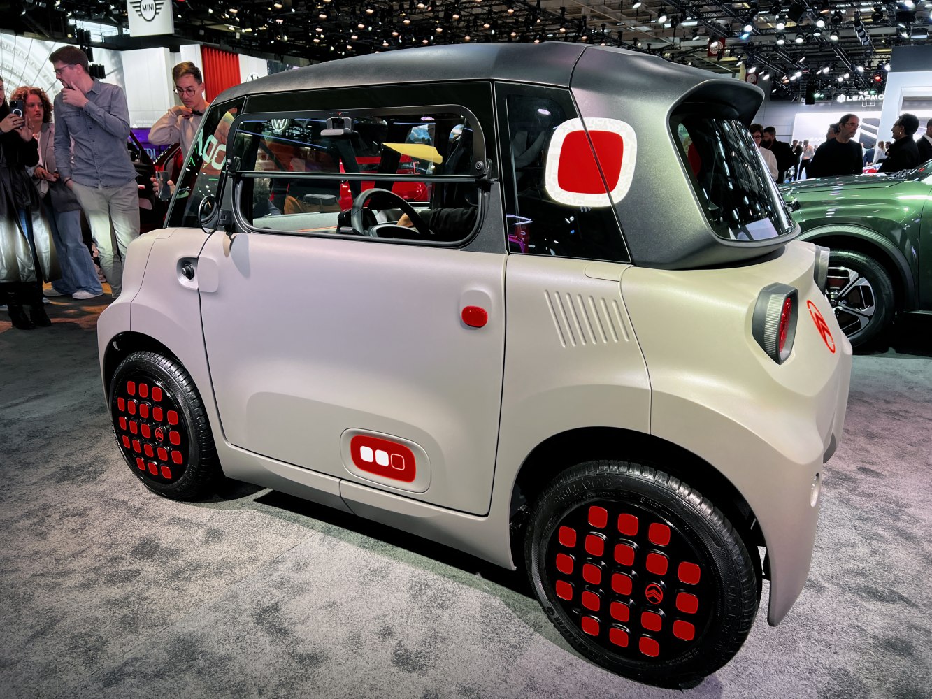 Compact electric urban vehicle with distinctive red accent details and rounded bodywork
