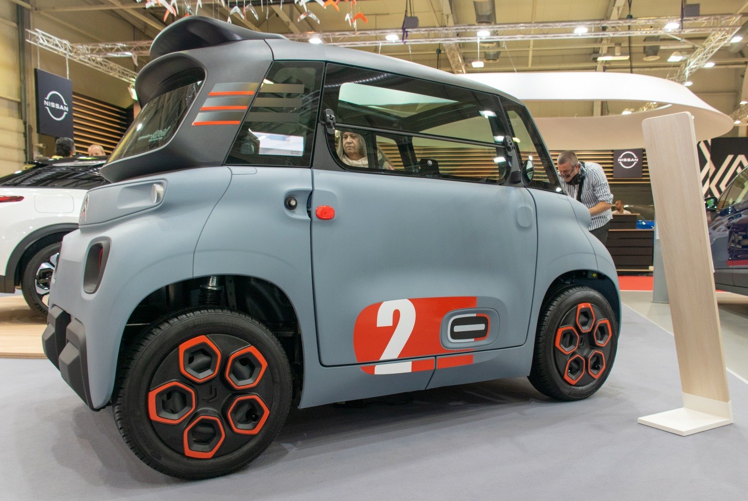 Compact electric vehicle with unique hexagonal orange-accented wheels.