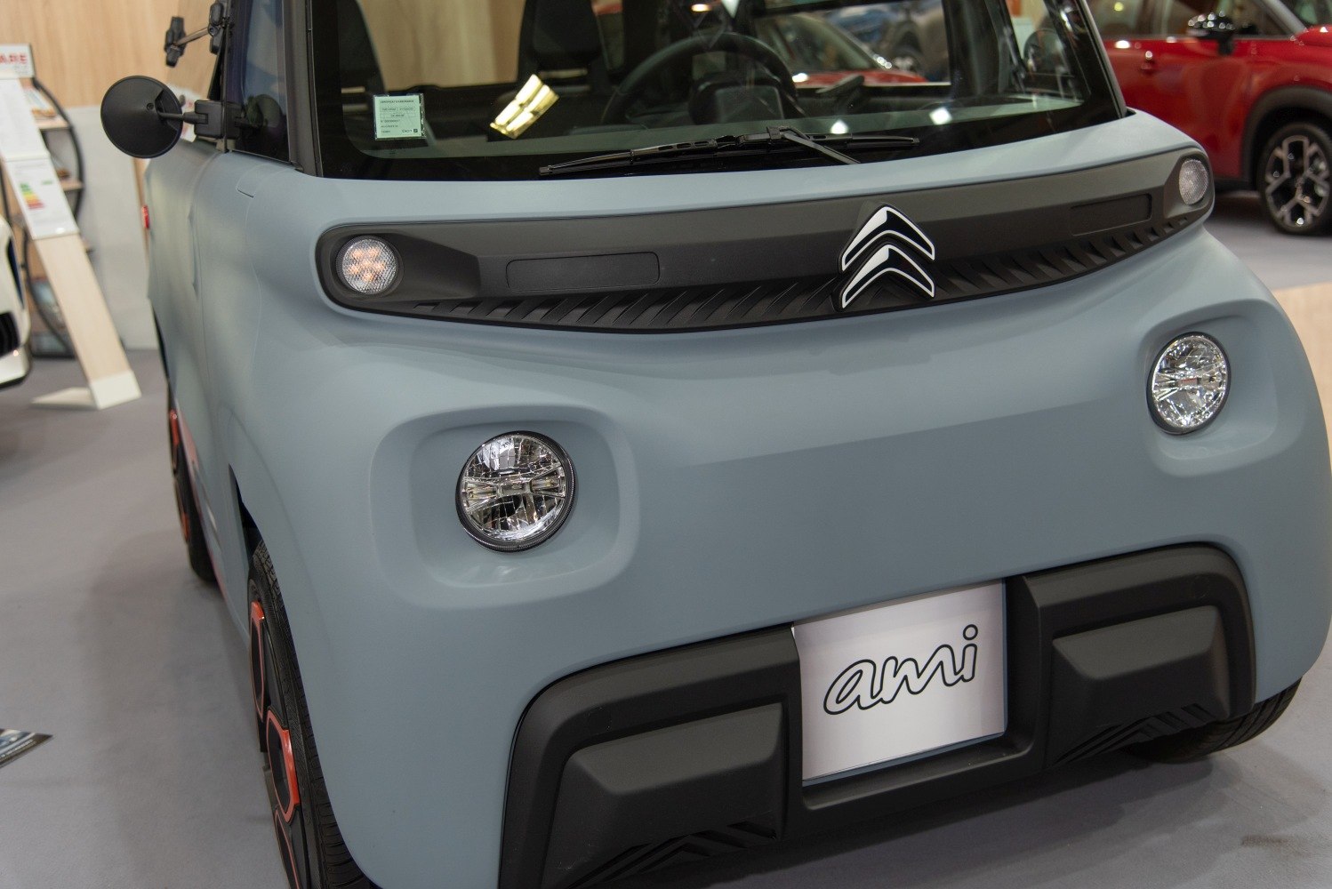 Compact electric vehicle front with round headlights and minimalist design