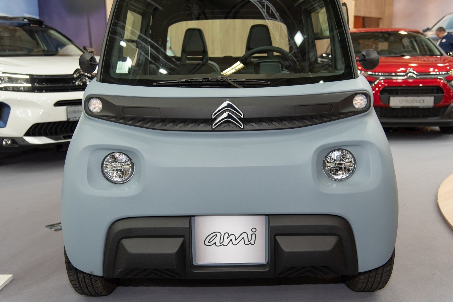Compact electric microcar front with dual round headlights and badge