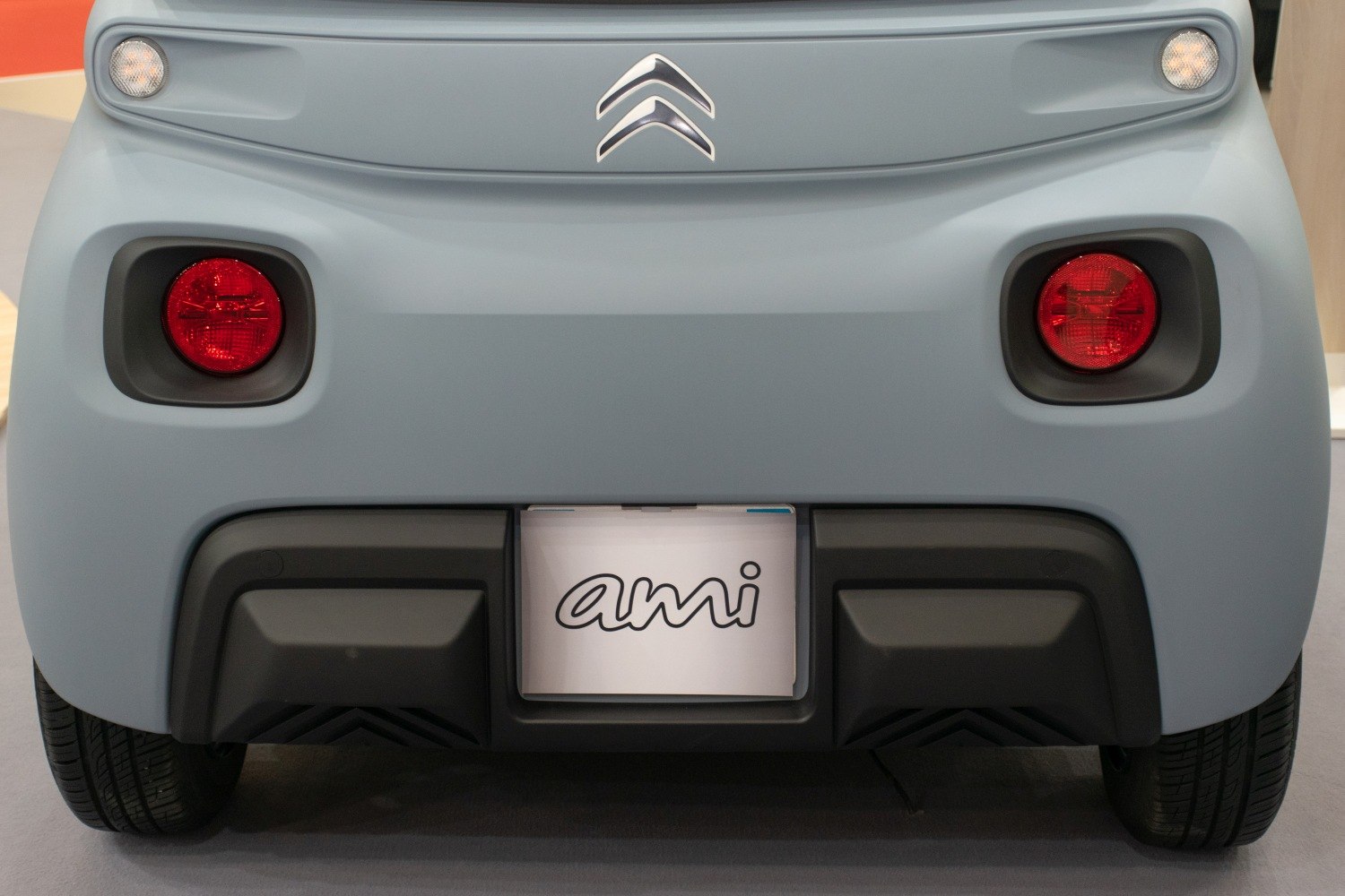 Rear end with round red tail lights and Ami badge on compact electric vehicle