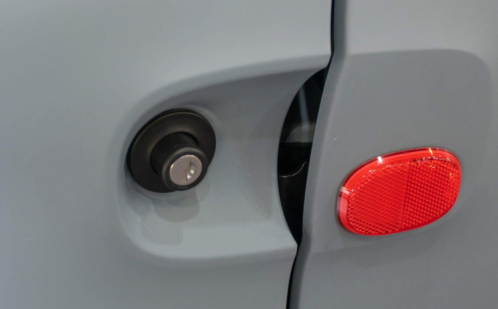 Close-up of side door lock and red reflector on vehicle door