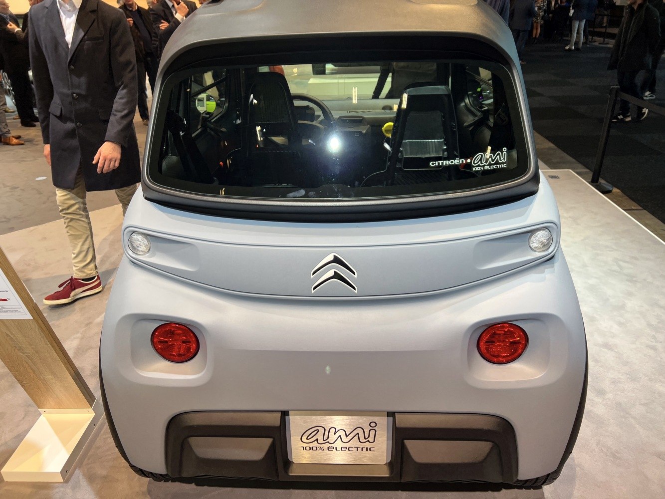 Compact electric vehicle rear with round red tail lights and large rear window