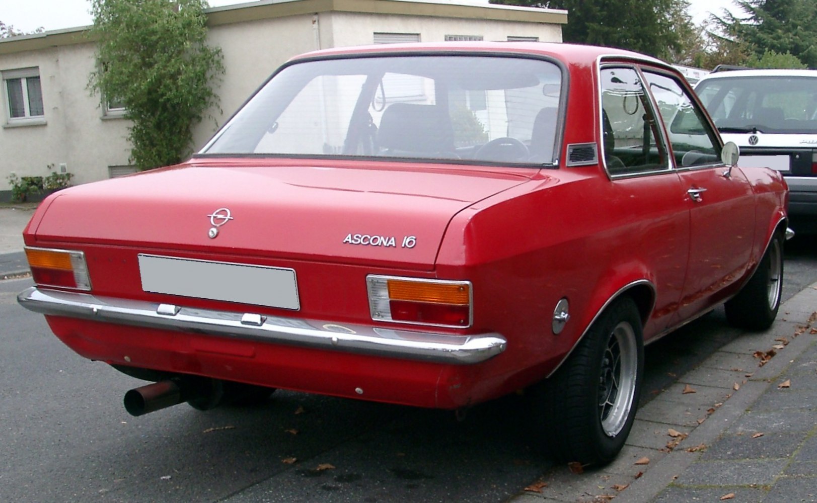 Rear view of classic red sedan with chrome bumper and retro tail lights.