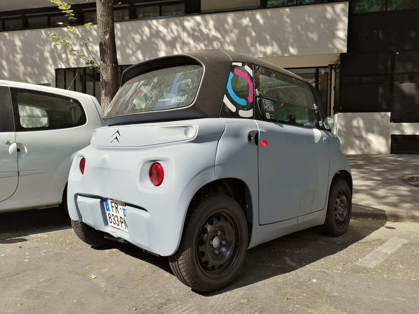 Rear angled view of compact electric vehicle with round taillights and minimalistic design.