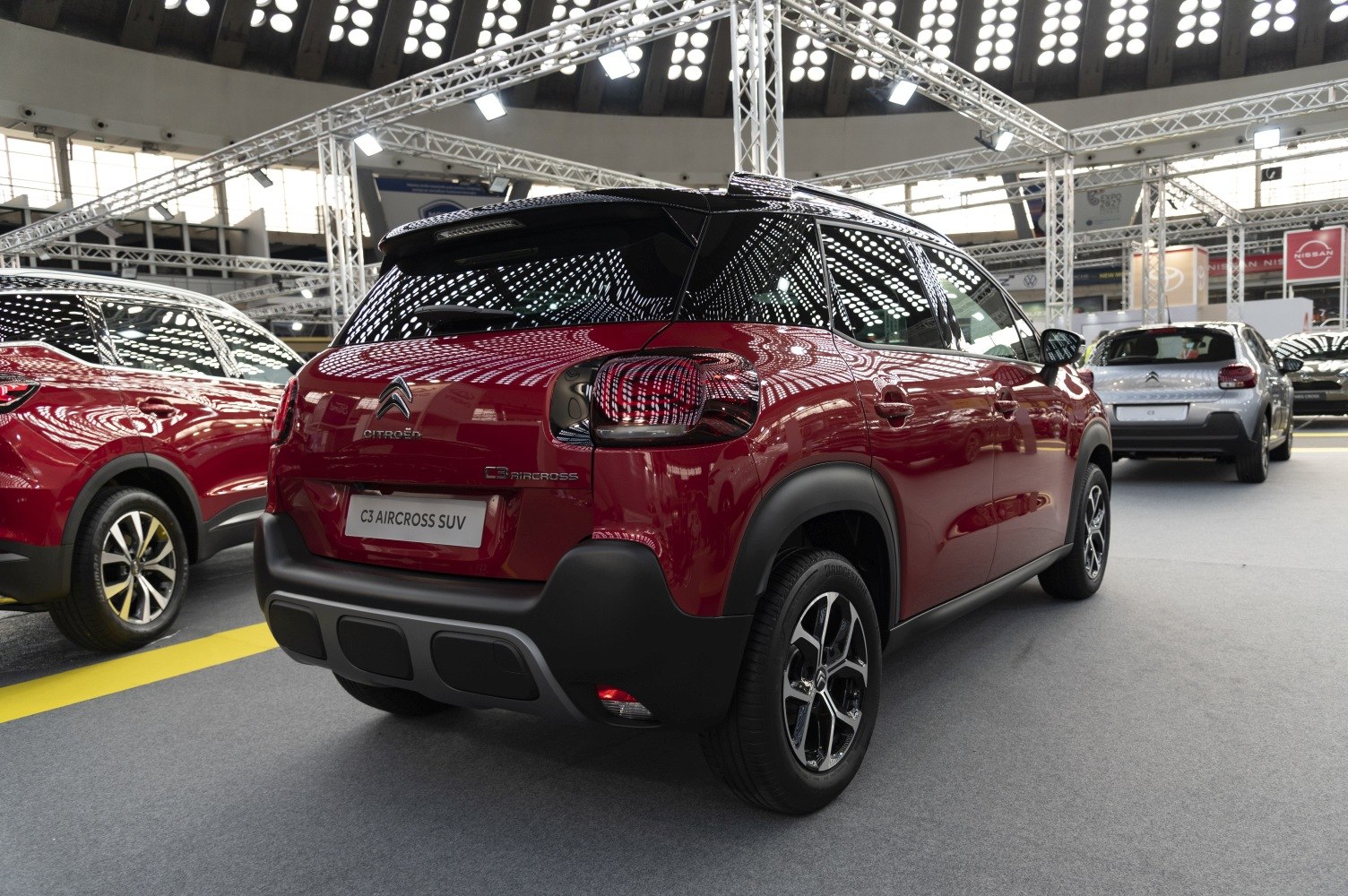 Rear and side view of a compact SUV with black roof and red body