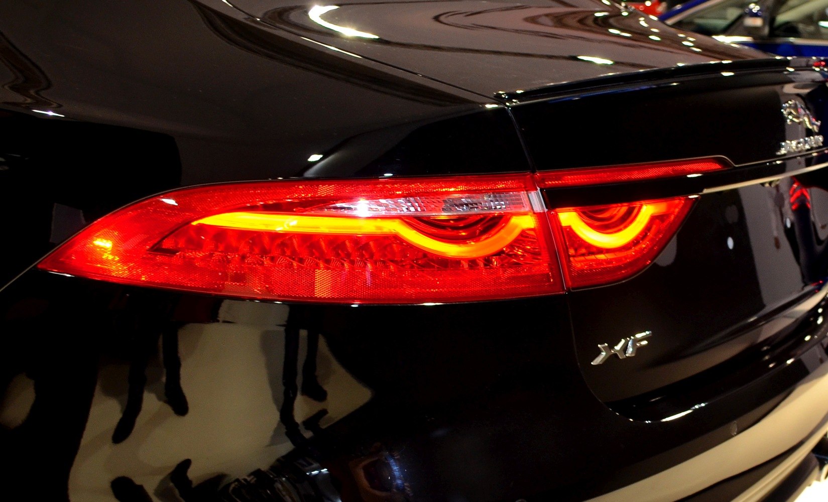 Close-up rear taillight with illuminated signature and XF badge on glossy black paint