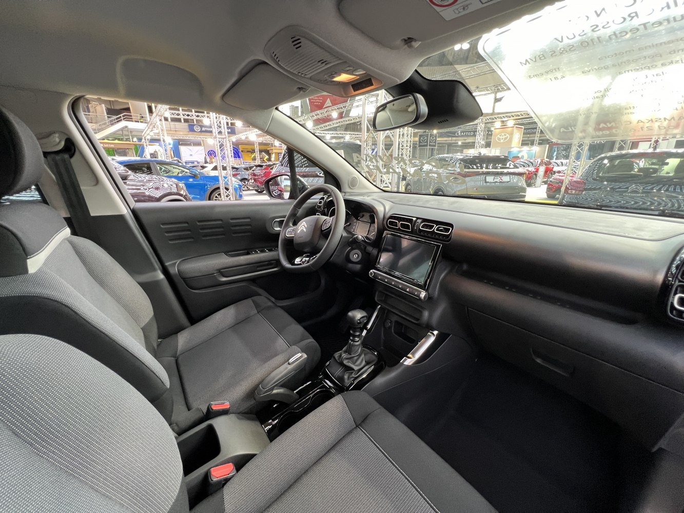 Modern car interior with dashboard, steering wheel, and fabric seats.