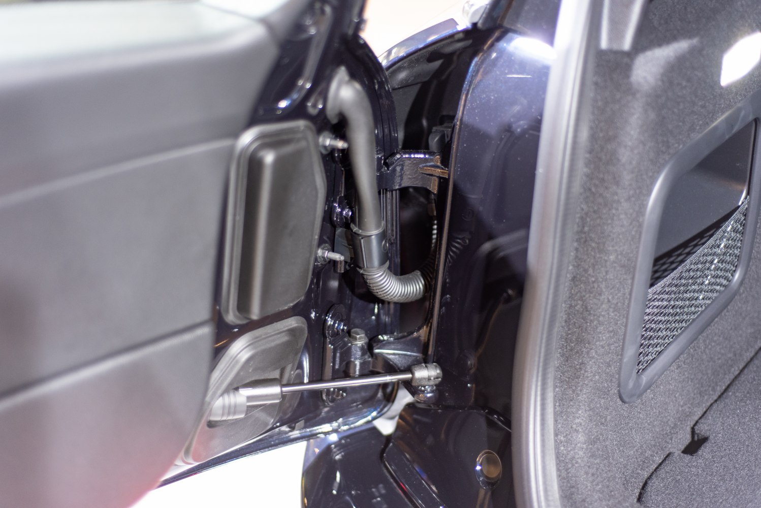 Close-up of door hinge, wiring conduit, and interior side panel.