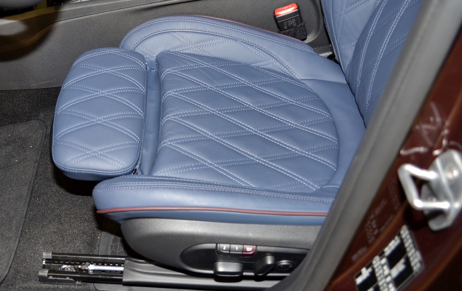 Blue quilted leather car seat with built-in adjustment controls.