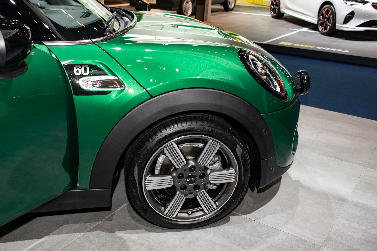 Front wheel, alloy rim, and fender trim of a green compact hatchback
