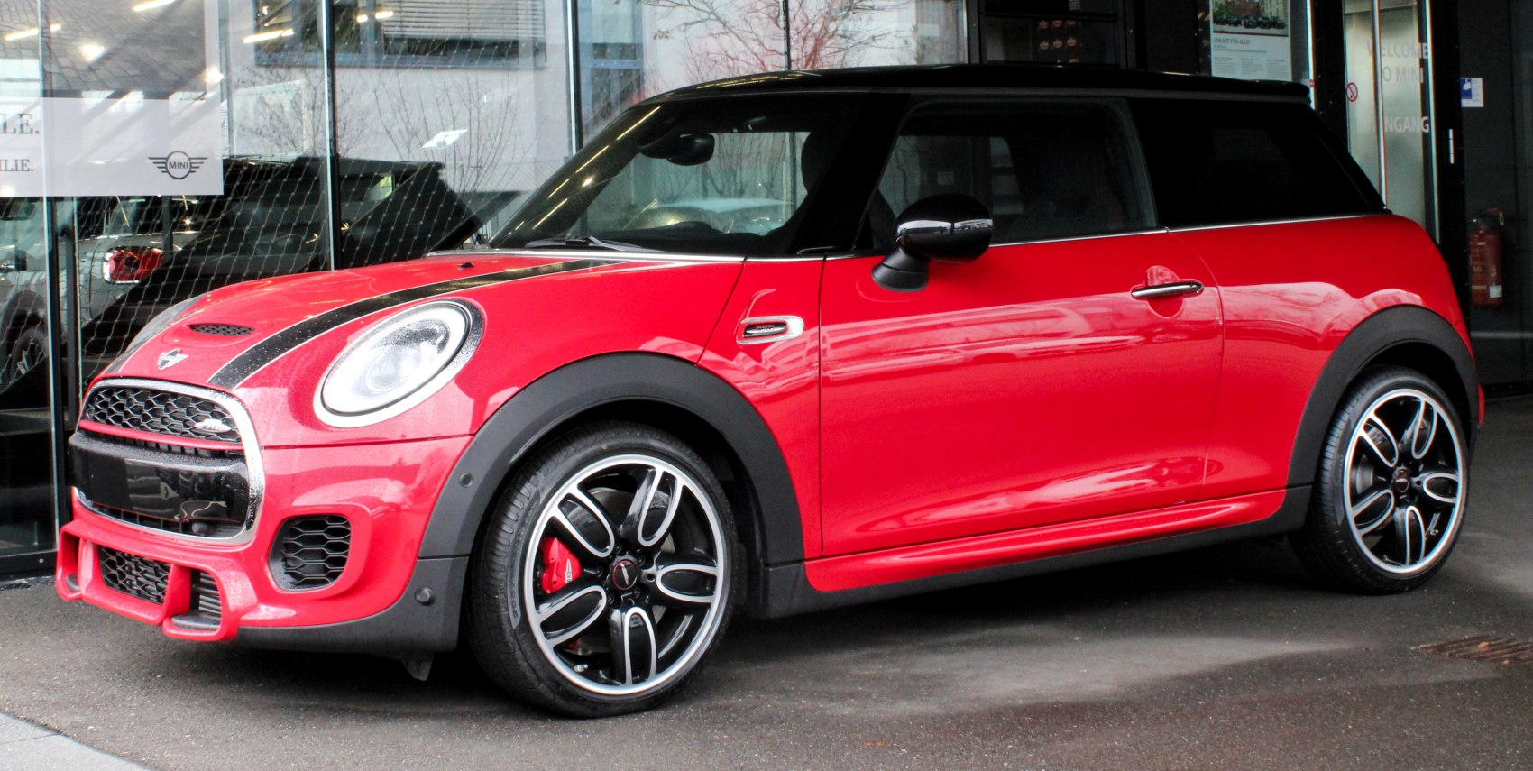 Red compact hatchback with black roof and racing stripes.